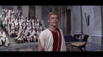 Movie still from “Cleopatra” (1963), directed by Rouben Mamoulian – A young man in a roman outfit stands in front of a group of people; Medium shot, Low angle