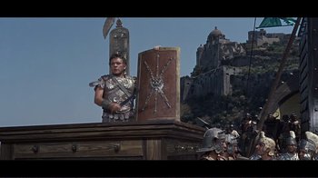 Movie still from “Cleopatra” (1963), directed by Rouben Mamoulian – A man in a roman soldier costume standing next to a wooden shield; Wide shot, Low angle