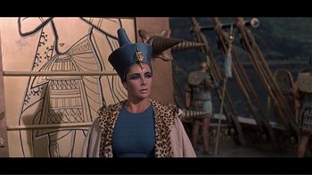 Movie still from “Cleopatra” (1963), directed by Rouben Mamoulian – A woman in a blue dress and a blue hat; Medium shot, Low angle