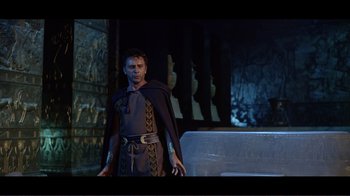 Movie still from “Cleopatra” (1963), directed by Rouben Mamoulian – A man in a black and gold outfit standing in front of a wall; Medium shot, Low angle