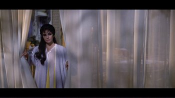 Movie still from “Cleopatra” (1963), directed by Rouben Mamoulian – A woman standing in front of a curtain; Medium shot, High angle