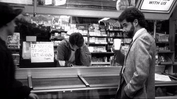 Movie still from “Clerks” (1994), directed by Kevin Smith – A man is standing at a counter in a grocery store; Medium shot, Low angle