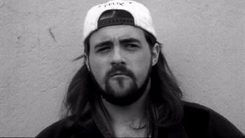 Movie still from “Clerks” (1994), directed by Kevin Smith – Black and white photograph of a man with long hair wearing a baseball cap; Close Up shot, Low angle