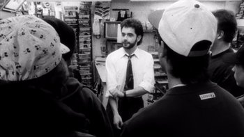 Movie still from “Clerks” (1994), directed by Kevin Smith – A group of people standing around a store; Medium shot, Over the shoulder angle