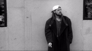 Movie still from “Clerks” (1994), directed by Kevin Smith – A black and white photo of a man with a long beard; Medium shot, Low angle