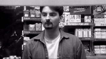 Movie still from “Clerks” (1994), directed by Kevin Smith – A black and white photo of a man standing in a store; Close Up shot, Low angle