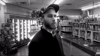 Movie still from “Clerks” (1994), directed by Kevin Smith – A man with a beard wearing a baseball cap; Close Up shot, Low angle