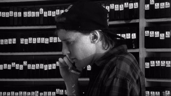 Movie still from “Clerks” (1994), directed by Kevin Smith – A young man in a black hat is talking on a cell phone; Close Up shot, High angle