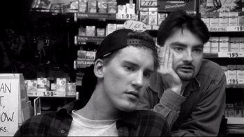 Movie still from “Clerks” (1994), directed by Kevin Smith – A man with a hat on and another man with a hand on his face; Close Up shot, Low angle