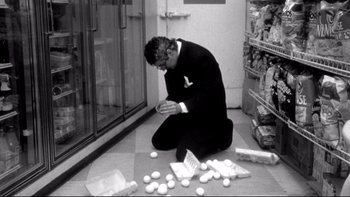 Movie still from “Clerks” (1994), directed by Kevin Smith – A man sitting on the floor in front of a pile of eggs; Medium shot, High angle