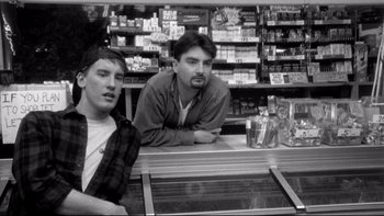 Movie still from “Clerks” (1994), directed by Kevin Smith – Two young men sitting at a counter in a store; Medium shot, Low angle