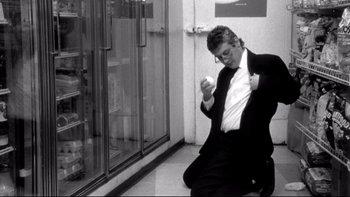 Movie still from “Clerks” (1994), directed by Kevin Smith – A black and white photo of a man in a suit and tie; Medium shot, Low angle