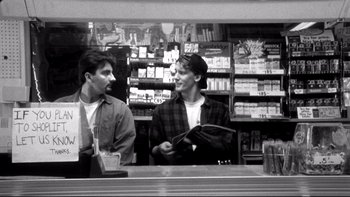 Movie still from “Clerks” (1994), directed by Kevin Smith – Two men standing at a counter in front of a store window; Medium shot, Low angle