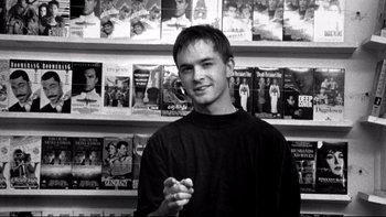 Movie still from “Clerks” (1994), directed by Kevin Smith – A man standing in front of a book case; Close Up shot, Low angle