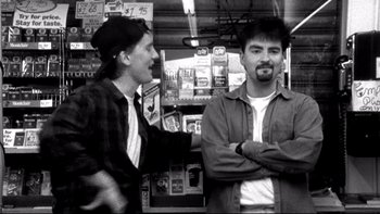 Movie still from “Clerks” (1994), directed by Kevin Smith – A couple of men standing next to each other in a store; Medium shot, Low angle