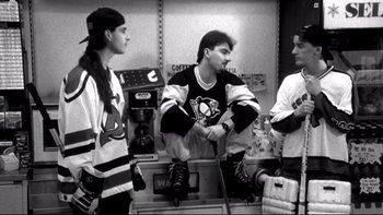 Movie still from “Clerks” (1994), directed by Kevin Smith – A group of men standing next to each other in a room; Medium shot, High angle