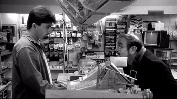 Movie still from “Clerks” (1994), directed by Kevin Smith – A man is talking to another man in a store; Medium shot, Over the shoulder angle