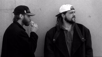 Movie still from “Clerks” (1994), directed by Kevin Smith – Two men standing next to each other in front of a wall; Close Up shot, Low angle