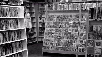 Movie still from “Clerks” (1994), directed by Kevin Smith – A black - and - white photo of a book store; Wide shot, Over the shoulder angle