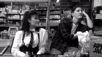 Movie still from “Clerks” (1994), directed by Kevin Smith – A man and a woman sitting next to each other in a store; Medium shot, Over the shoulder angle