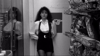 Movie still from “Clerks” (1994), directed by Kevin Smith – A black and white photo of a woman standing in front of a soda case; Medium shot, Over the shoulder angle