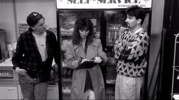 Movie still from “Clerks” (1994), directed by Kevin Smith – A woman standing next to two other men; Medium shot, Over the shoulder angle
