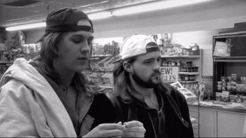 Movie still from “Clerks” (1994), directed by Kevin Smith – Two men standing next to each other in front of a building; Close Up shot, Low angle