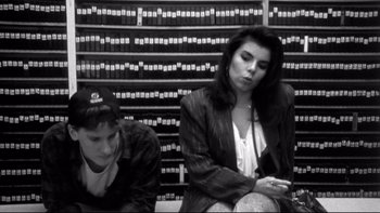 Movie still from “Clerks” (1994), directed by Kevin Smith – A woman and a man sitting in front of a wall of law books; Medium shot, High angle