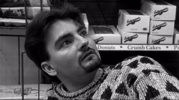 Movie still from “Clerks” (1994), directed by Kevin Smith – A black and white photo of a man in a donut shop; Close Up shot, Low angle