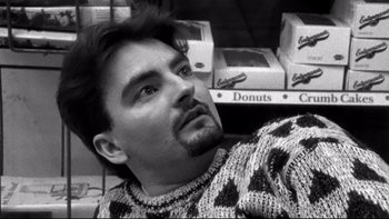 Movie still from “Clerks” (1994), directed by Kevin Smith – A black and white photo of a man in a donut shop; Close Up shot, Low angle