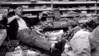 Movie still from “Clerks” (1994), directed by Kevin Smith – A person laying on the ground in a store; Wide shot, Overhead angle