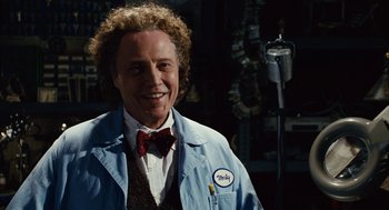 Movie still from “Click” (2006), directed by Frank Coraci – A man with curly blonde hair wearing a blue lab coat; Medium shot, Over the shoulder angle
