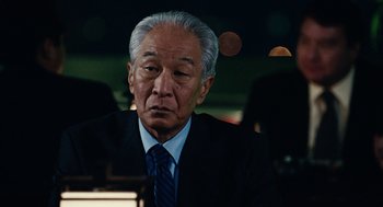 Movie still from “Click” (2006), directed by Frank Coraci – An older man wearing a suit and tie; Close Up shot, Over the shoulder angle