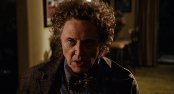 Movie still from “Click” (2006), directed by Frank Coraci – An older man with curly brown hair and a bow tie; Close Up shot, Over the shoulder angle