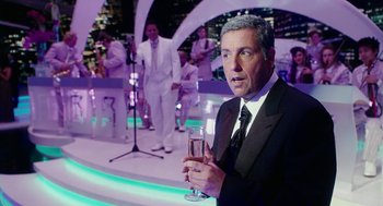 Movie still from “Click” (2006), directed by Frank Coraci – A man in a suit holding a glass of champagne; Medium shot, Over the shoulder angle