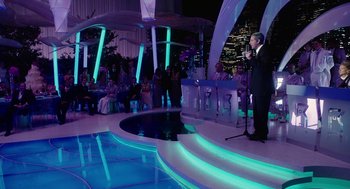 Movie still from “Click” (2006), directed by Frank Coraci – A man standing in front of an audience in front of a swimming pool; Wide shot, High angle