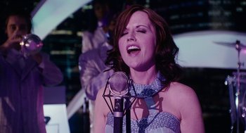 Movie still from “Click” (2006), directed by Frank Coraci – A woman singing into a microphone in front of a crowd; Medium shot, Low angle