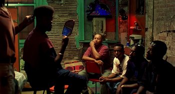Movie still from “Clockers” (1995), directed by Spike Lee – A group of men sitting in a room next to each other; Medium shot, Over the shoulder angle