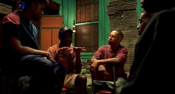 Movie still from “Clockers” (1995), directed by Spike Lee – A group of people sitting around a room; Medium shot, High angle