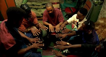 Movie still from “Clockers” (1995), directed by Spike Lee – A group of people sitting in a circle with their hands in the air; Medium shot, High angle