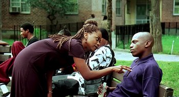 Movie still from “Clockers” (1995), directed by Spike Lee – A young woman leaning over a man on a park bench; Medium shot, Over the shoulder angle