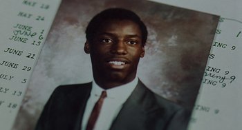 Movie still from “Clockers” (1995), directed by Spike Lee – A man in a suit and tie in front of a picture; Extreme Close Up shot, Overhead angle