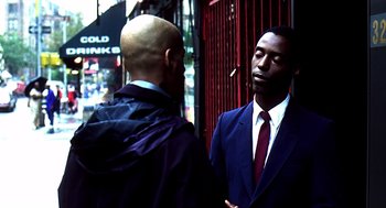 Movie still from “Clockers” (1995), directed by Spike Lee – A man in a blue suit talks to another man in a red tie; Medium shot, Over the shoulder angle