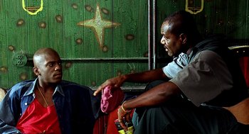 Movie still from “Clockers” (1995), directed by Spike Lee – Two men are sitting in front of a green wall; Medium shot, Low angle