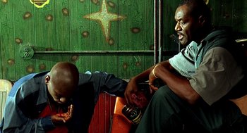 Movie still from “Clockers” (1995), directed by Spike Lee – Two men sitting next to each other in front of a green wall; Medium shot, Low angle