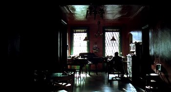 Movie still from “Clockers” (1995), directed by Spike Lee – A man sitting at a desk in a room with two large windows; Wide shot, Low angle
