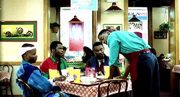 Movie still from “Clockers” (1995), directed by Spike Lee – Three men sitting at a table in front of a waiter; Medium shot, Over the shoulder angle