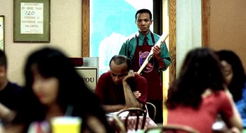 Movie still from “Clockers” (1995), directed by Spike Lee – A man standing in front of another man holding a wooden stick; Medium shot, Over the shoulder angle