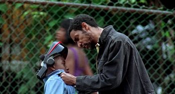 Movie still from “Clockers” (1995), directed by Spike Lee – A man is helping a young boy put on a tie; Medium shot, Over the shoulder angle