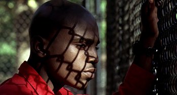Movie still from “Clockers” (1995), directed by Spike Lee – A man's face with a chain - link fence in the background; Close Up shot, Low angle